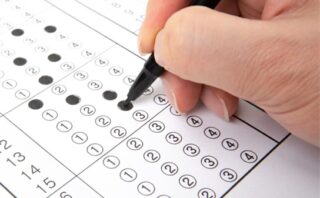 A picture of a hand holding a pen and a 5 point survey which is part-filled in