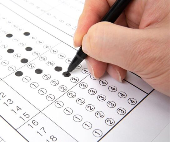 A picture of a hand holding a pen and a 5 point survey which is part-filled in