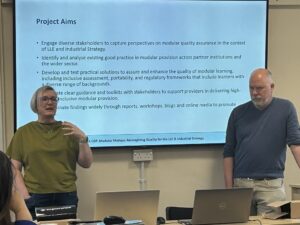 Two presenters at a conference speaking in front of their slide